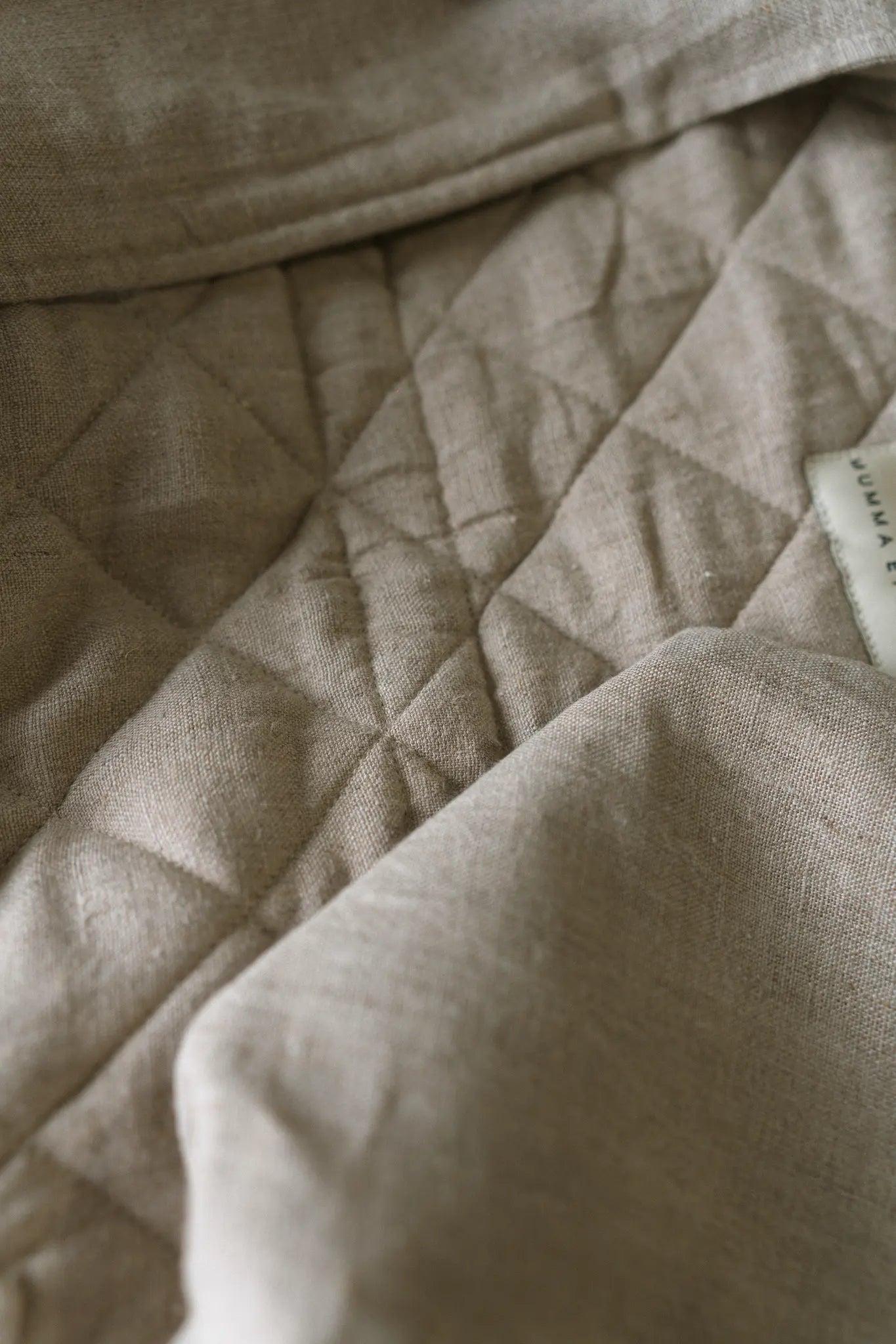 Close detail of diamond quilting stitched into natural flax linen on a Mumma Etcetera baby carrier