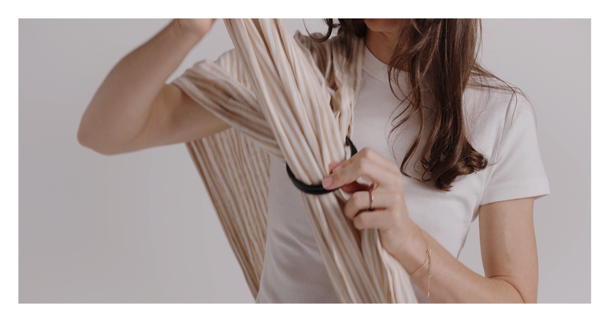 Close look at threading the gathered linen tail through the black rings of the Sling Carrier at the shoulder
